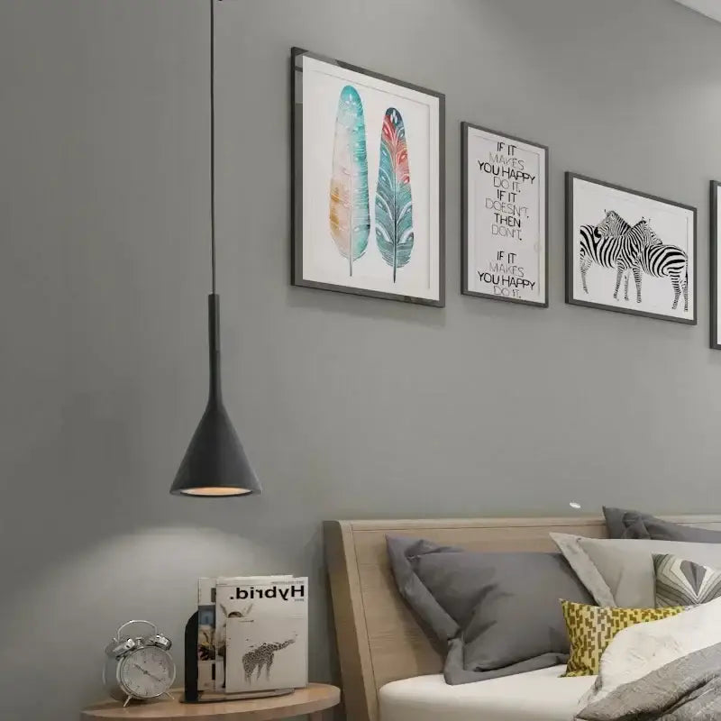 Black metal modern nordic pendant light with conical design hanging above wooden nightstand in bedroom setting
