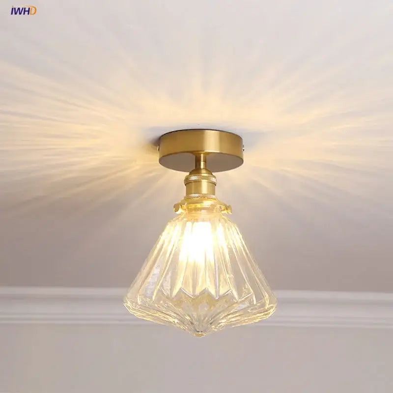 A modern Nordic brass and diamond glass led ceiling light with a clear faceted glass pendant for bedrooms