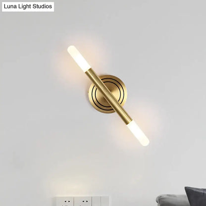 Modern nordic brass finish wall sconce with sleek cylindrical design and two frosted glass light fixtures for bedroom use