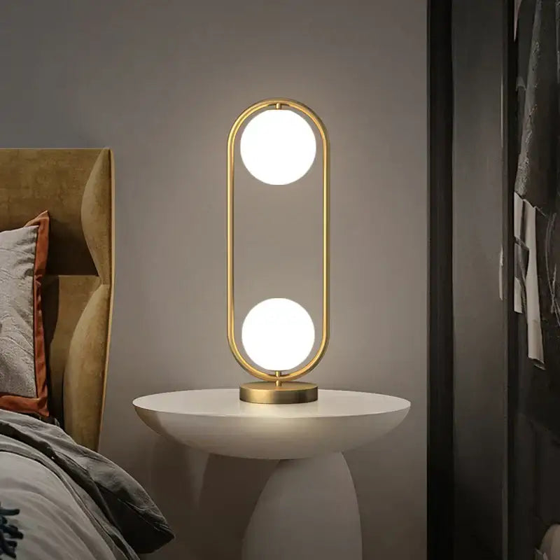 Modern nordic golden body glass led desk lamp with gold-toned oval frame and two glowing bulbs for stylish decorbites lighting