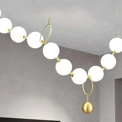 A modern nordic led pendant lamp with white spherical glass bulbs and gold-toned metal rings for dining room decorbites