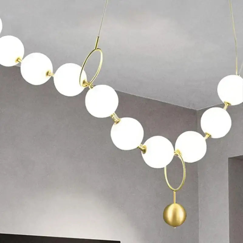 A modern nordic led pendant lamp with white spherical glass bulbs and gold-toned metal rings for dining room decorbites