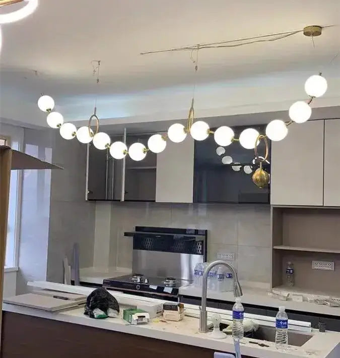 Modern nordic led pendant lamp with white spherical bulbs and gold-toned arms suspended above kitchen counter decorbites nordic led
