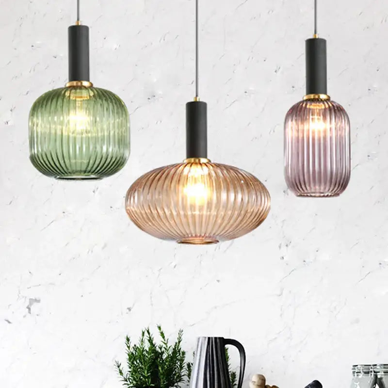 Three modern nordic ribbed glass led pendant lights in green amber and mauve with black stems and gold accents for dining room