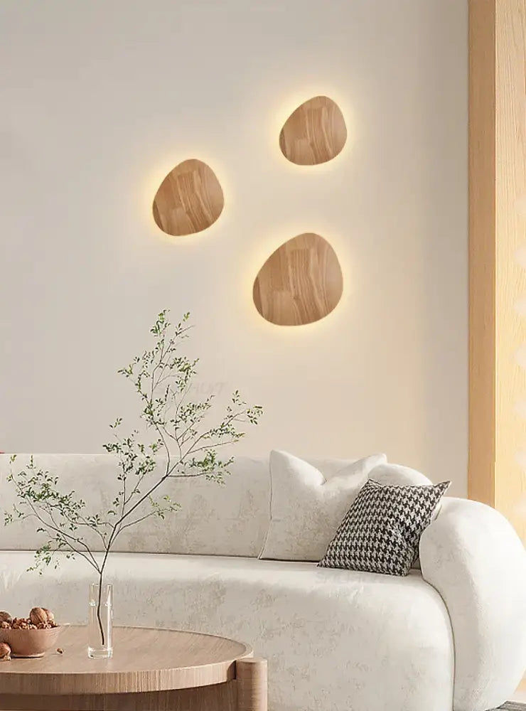 Three oval-shaped modern nordic eclipse wooden wall lamps with warm glowing backlight for bedroom use