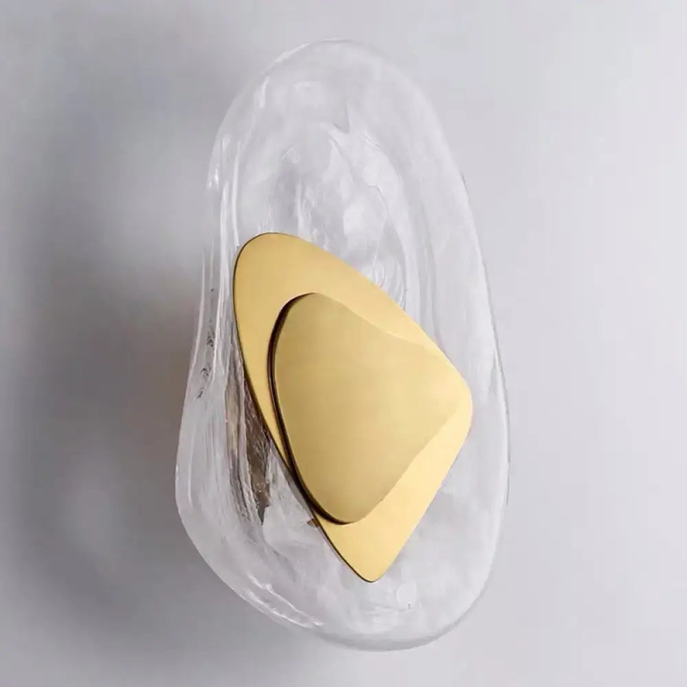 Modern nordic sconce light fixture with a sleek translucent glass wall and polished gold triangular accent for bedrooms