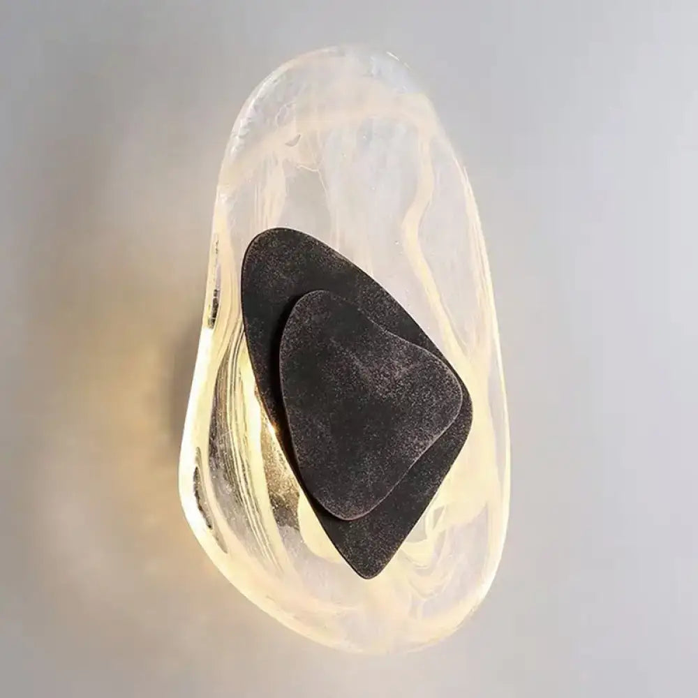 Transparent smooth glass container holding three nested black guitar picks for modern nordic sconce light fixture