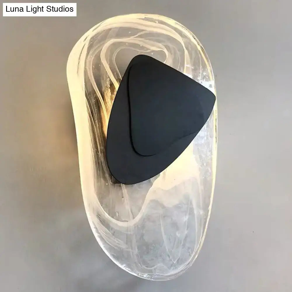 Modern nordic sconce light fixture with a swirling translucent glass body and black metallic antique triangular shade