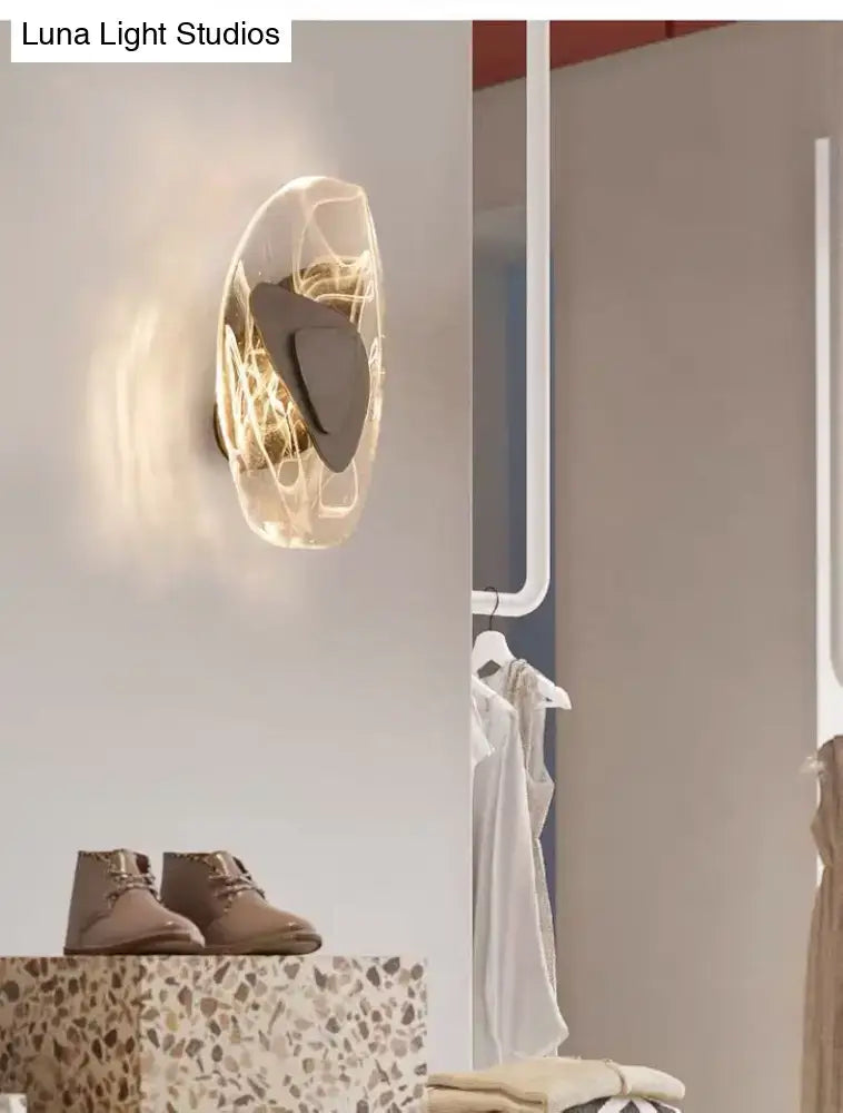 Modern nordic sconce light fixture with translucent sculpted glass body and black metallic antique accents for bedroom use