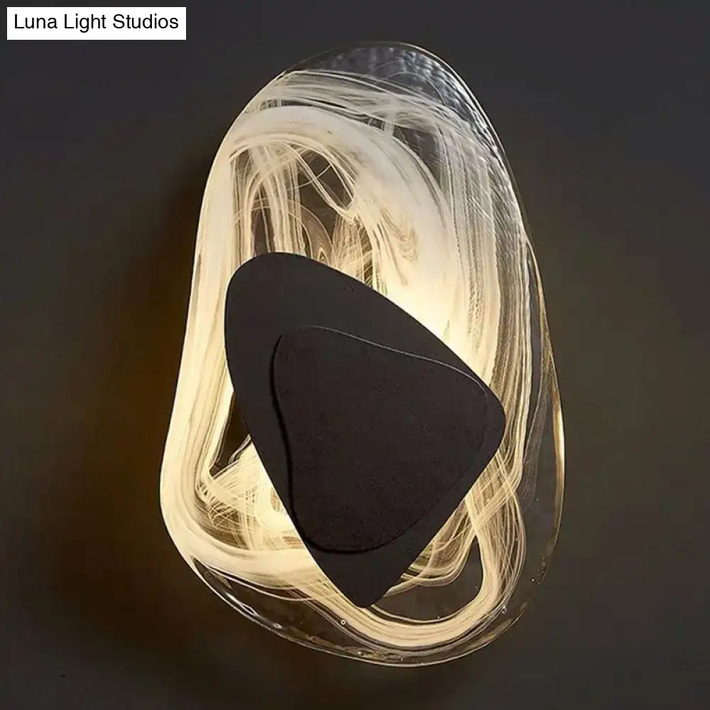 Modern nordic sconce light fixture with translucent swirling glass body and black metallic antique layered accents