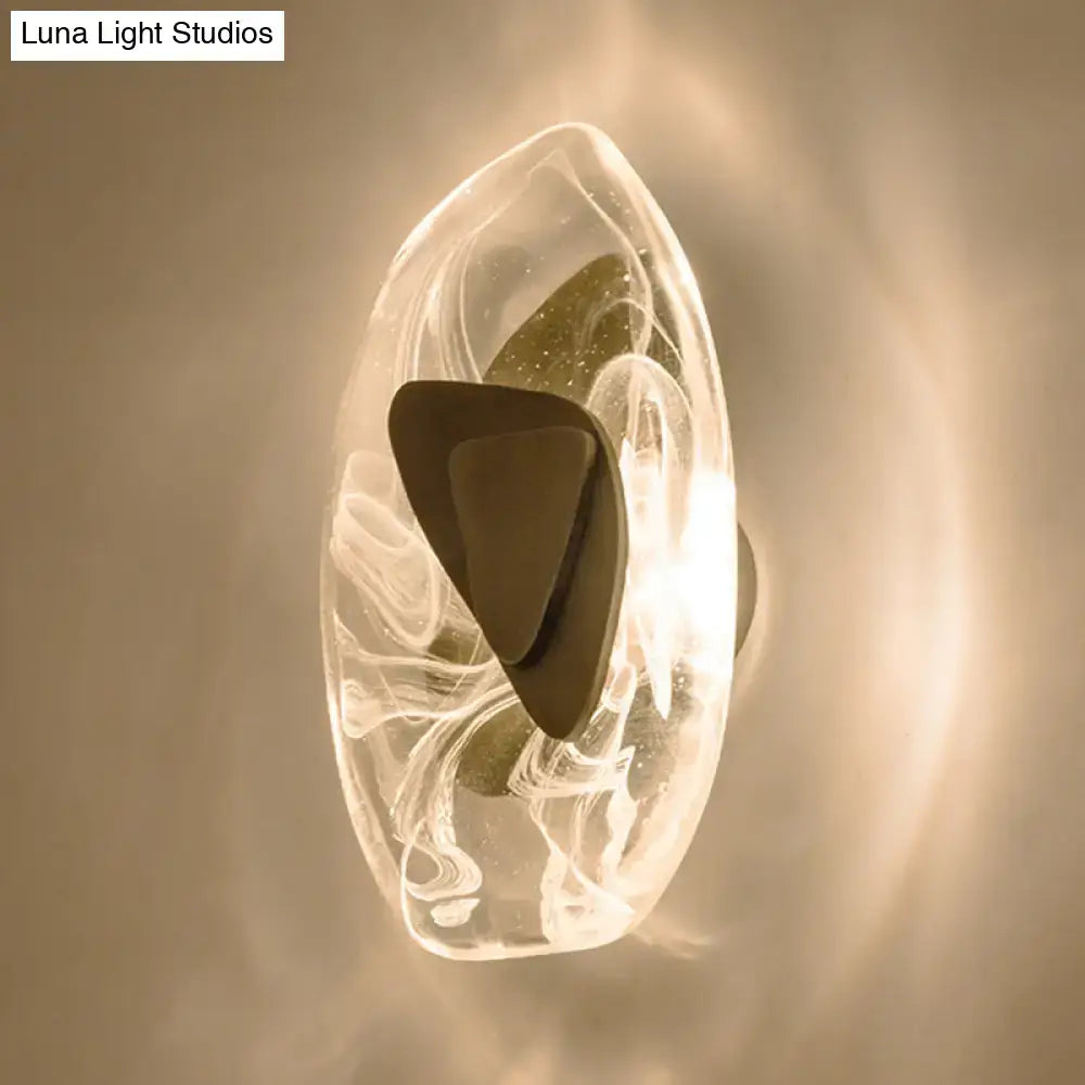 A modern nordic sconce light fixture with a clear glass shell, swirling white patterns, and black metallic antique accent