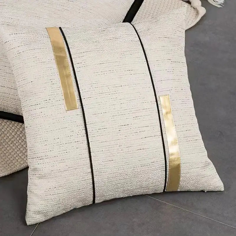 Modern off-white cushion cover with black stripe jaquard design featuring two gold metallic stripes and black piping