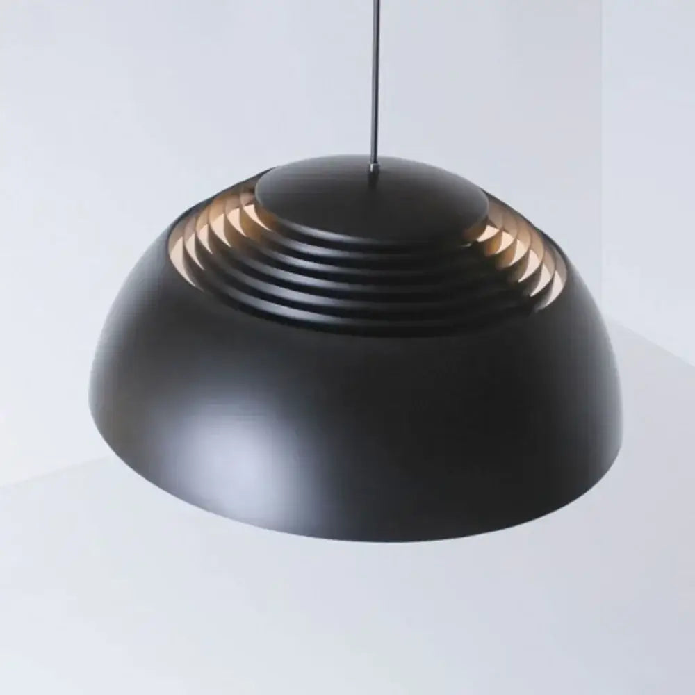 Black matte pendant light with concentric ridges and warm glow complements decorbites glass ball pendant for dining room