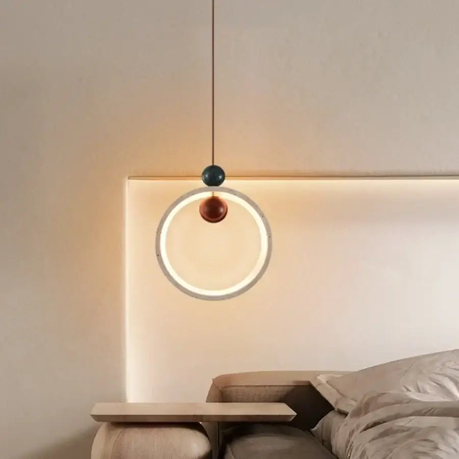 Modern off-white travertine adjustable led pendant light with circular ring frame softly glowing above a bed decorbites adjustable led pendant