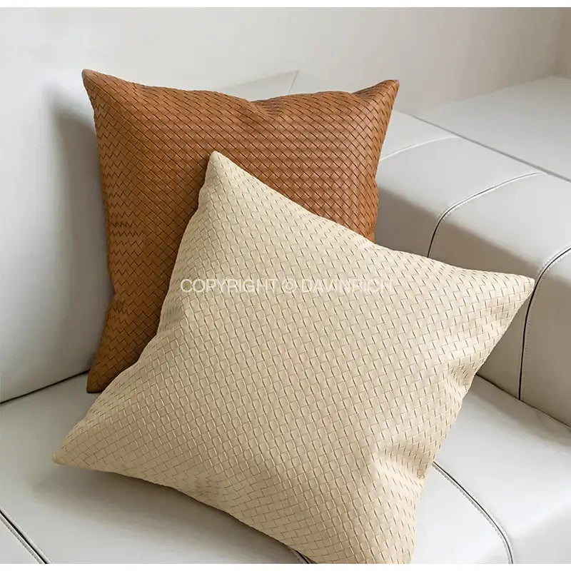 Two woven square throw pillows in warm tan and creamy off-white with decorbites geometric faux leather pillow cover