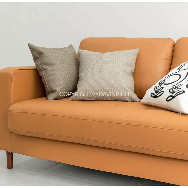 Warm orange leather sofa with tufted seat and armrests featuring modern olive green geometric faux leather pillow cover decorbites geometric faux pillow cover