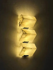 Three stacked rectangular onyx sconces with warm amber glow and natural veining modern geometric led outdoor wall light
