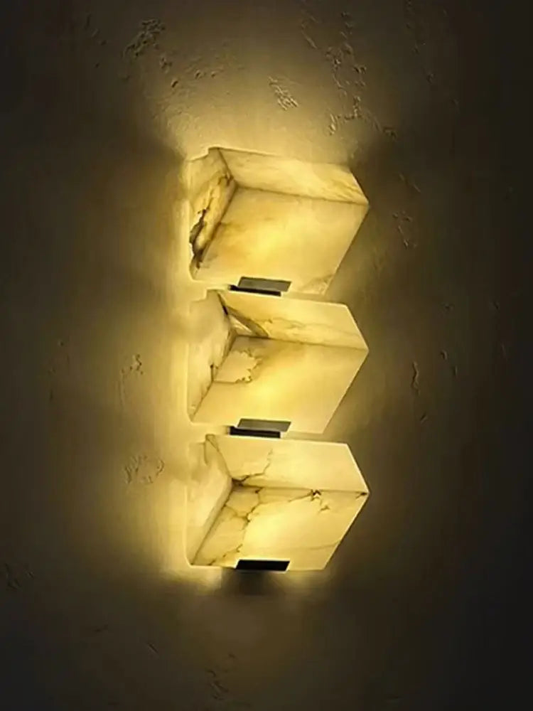 Three stacked rectangular onyx sconces with warm amber glow and natural veining modern geometric led outdoor wall light