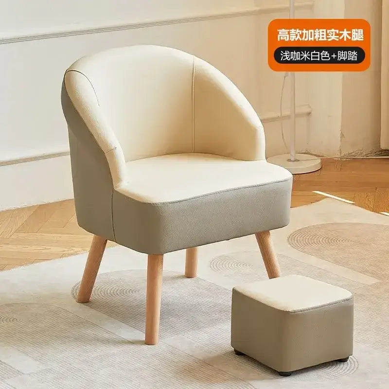 Cream-colored upholstered single sofa chair with rounded back and wooden legs paired with matching footstool