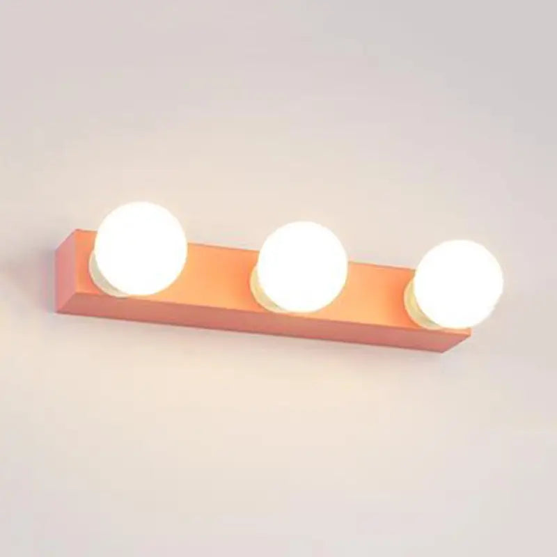 Modern orange and white vanity light fixture with three round white bulbs designed for bedroom use