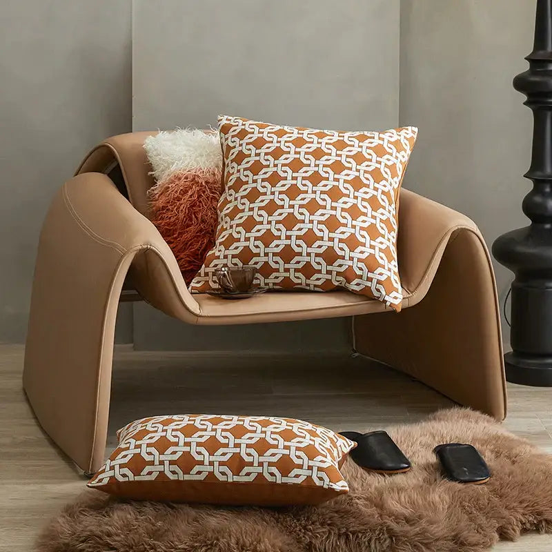 Tan leather armchair with sleek curved design and modern orange and white decorbites jacquard crochet pillow covers