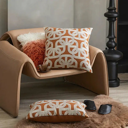 Tan leather armchair with modern curved design featuring modern orange and white decorbites jacquard crochet pillow covers
