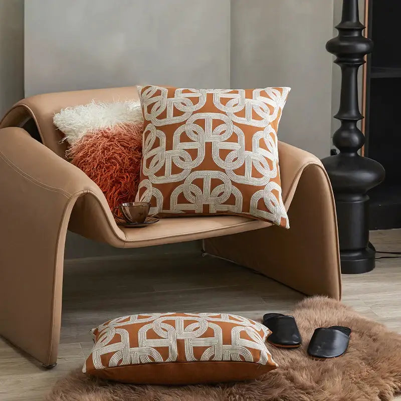 Tan leather armchair with modern curved design featuring modern orange and white decorbites jacquard crochet pillow covers