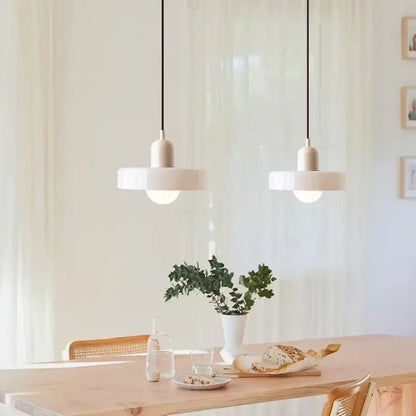 Two minimalist white glass led macaron pendant lights with sleek design hang above a wooden dining table