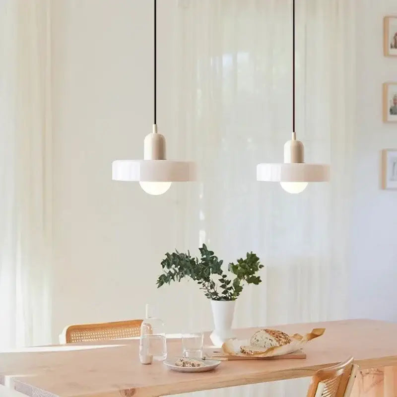 Two minimalist white glass led macaron pendant lights with sleek design hang above a wooden dining table