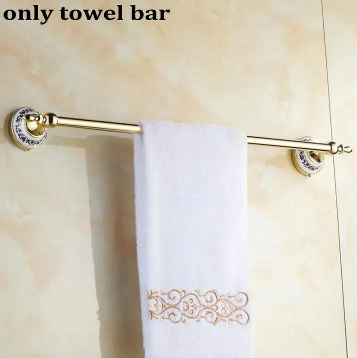 Modern ornate gold and white porcelain bath hardware set with gold-toned towel bar and white embroidered towel