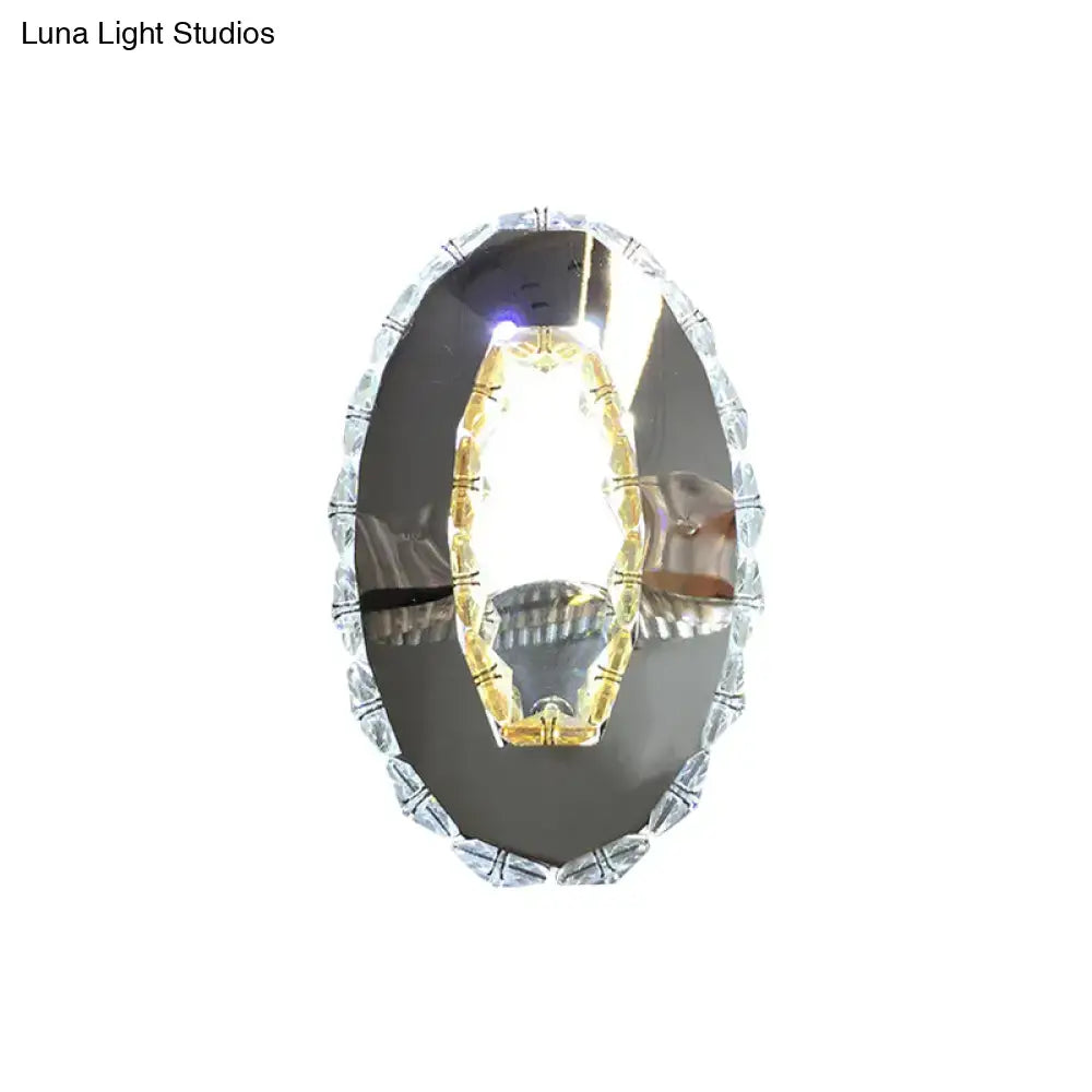 Modern oval chrome crystal wall sconce with silver oval mirror and beaded edge reflecting warm white light inch fixture