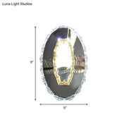 Modern oval chrome crystal wall sconce with warm white light and mirrored surface for bedroom lighting