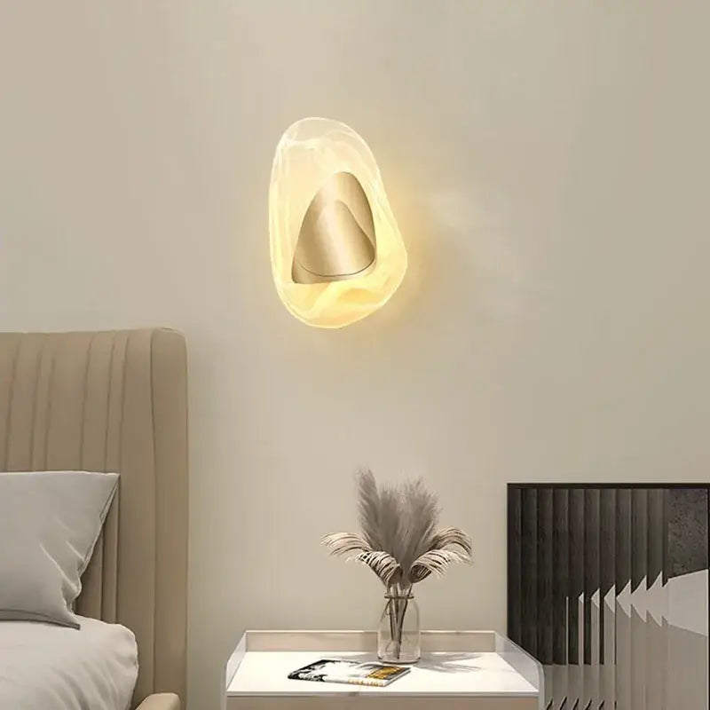 Modern oval crystal wall lamp with a translucent warm acrylic shell and metallic cone for bedroom use