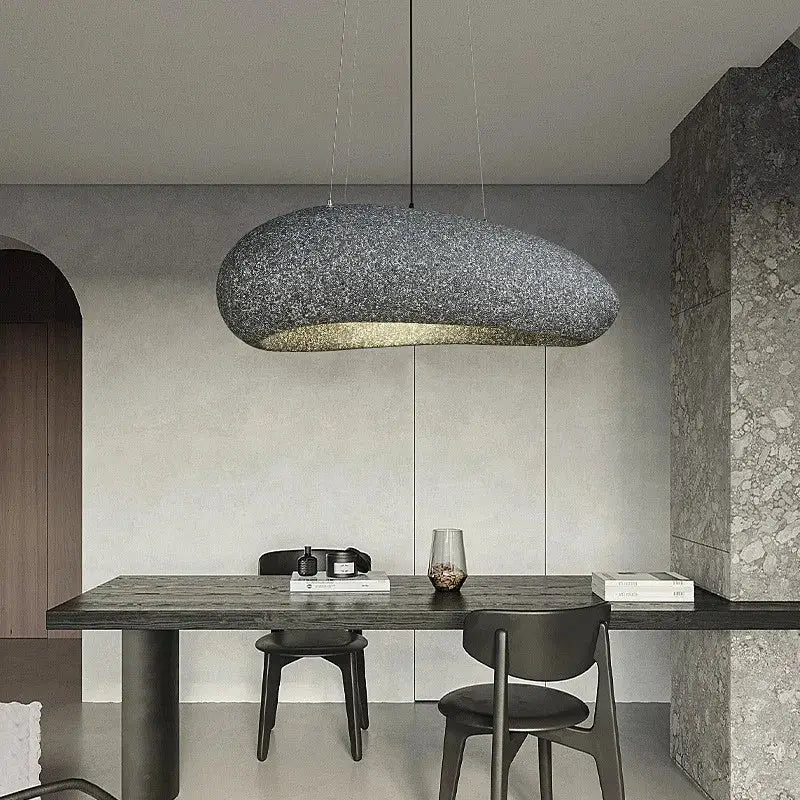 A modern oval gray and gold pendant light with textured surface and warm glow for decorbites loft dining room decor