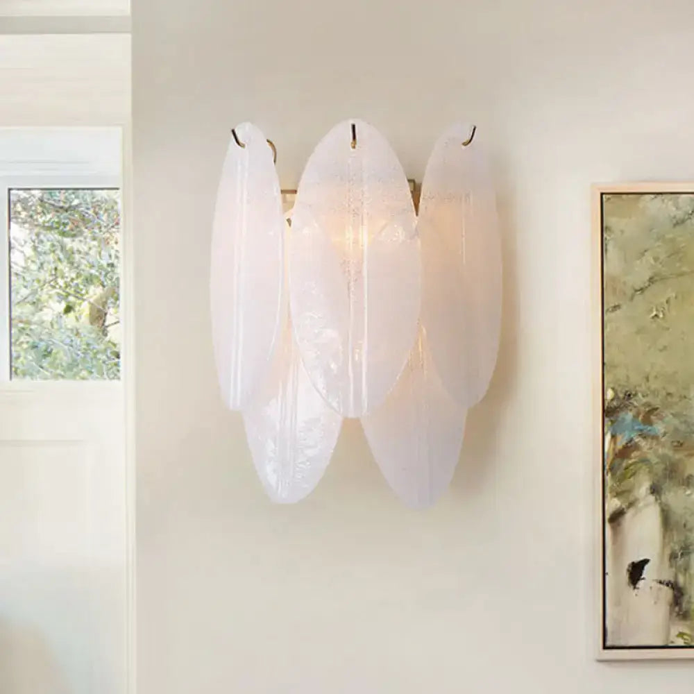 Modern oval white glass wall sconce shaped like a translucent leaf with a central light source for hallway use