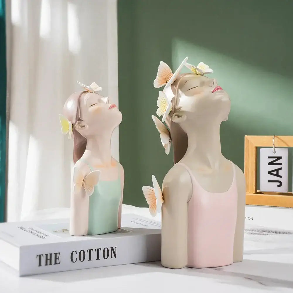 Two pastel-colored resin butterfly girl sculptures in mint green and soft pink with closed eyes for bedroom decor
