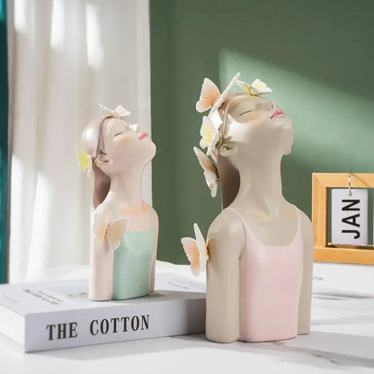 Two pastel-colored resin butterfly girl sculptures in mint green and soft pink with closed eyes for bedroom decor