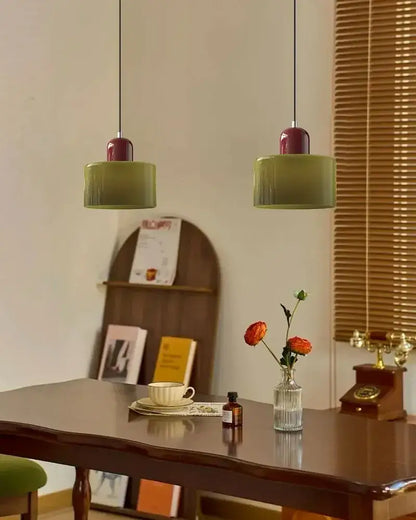 Two olive-green cylindrical pendant lights with burgundy stained glass shade tops for kitchen and dining room use