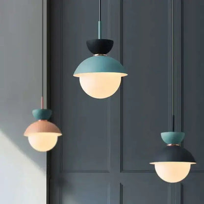 Modern pastel matte ceramic glass ball pendant lamp with matte teal and black upper halves and warm glowing frosted domes