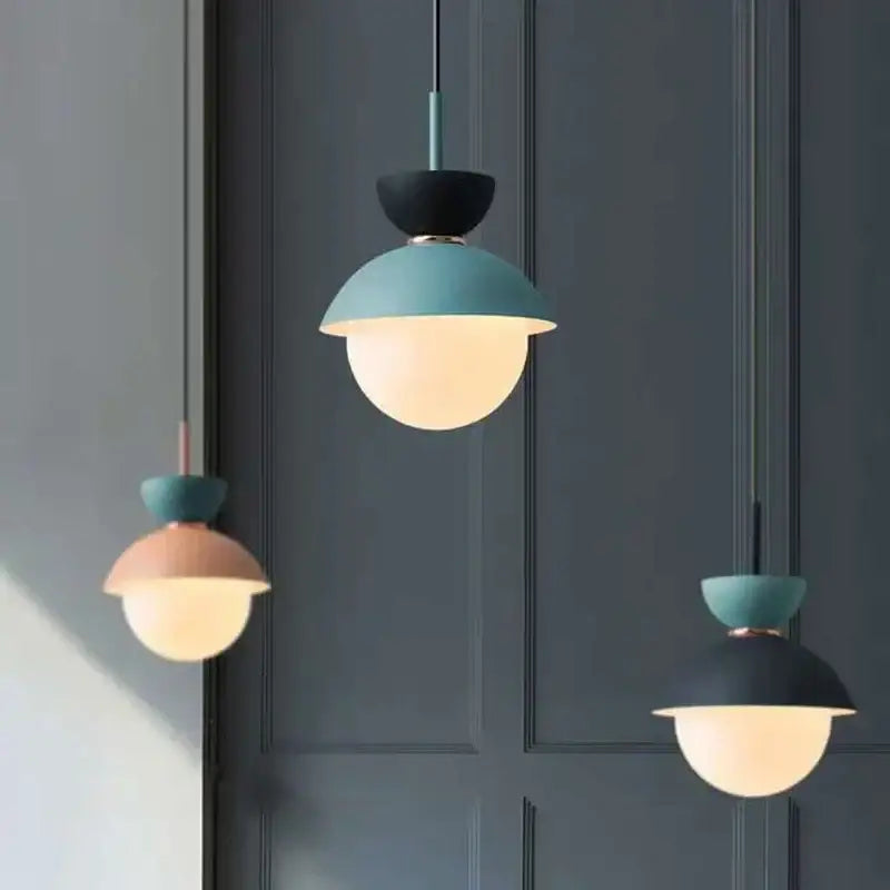 Modern pastel matte ceramic glass ball pendant lamp with matte teal and black upper halves and warm glowing frosted domes