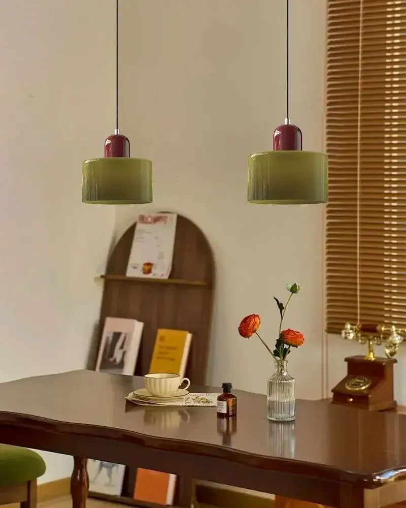 Two olive green cylindrical cord pendant lights with burgundy tops in modern pastel stained glass kitchen set