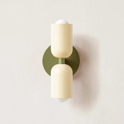 Cream-colored cylindrical decorbites led wall sconce with matte finish and olive green backplate for modern led wall lights