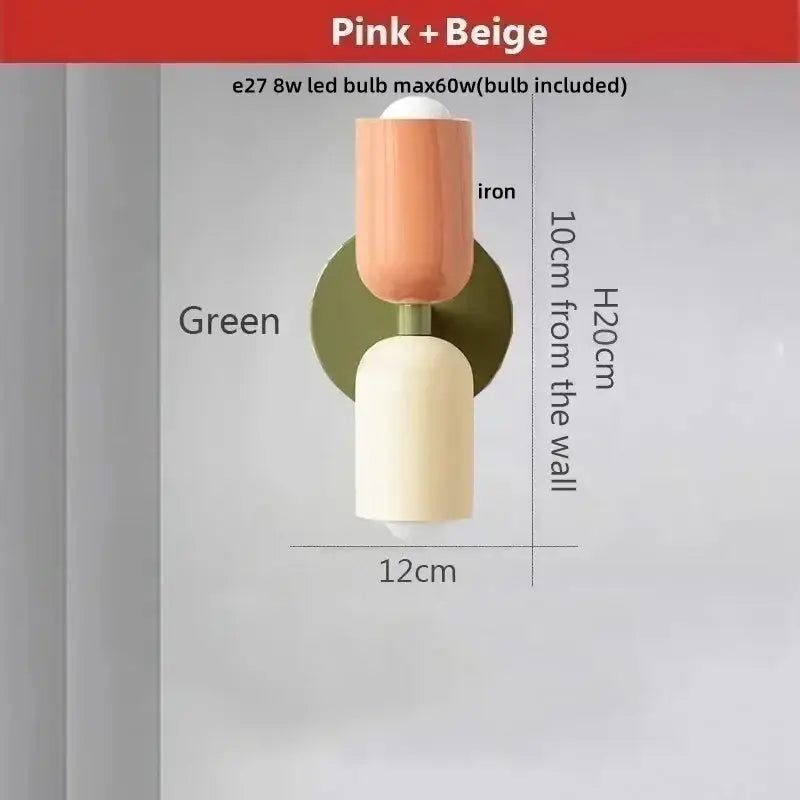 A modern decorbites led wall sconce with peach and cream cylindrical design and iron green circular backplate