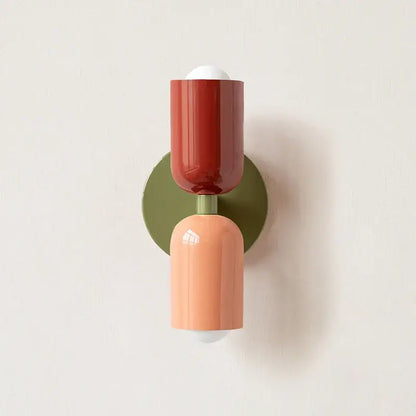 A modern two-tiered led wall light with glossy terracotta and matte peach shades on an olive green base by decorbites led wall