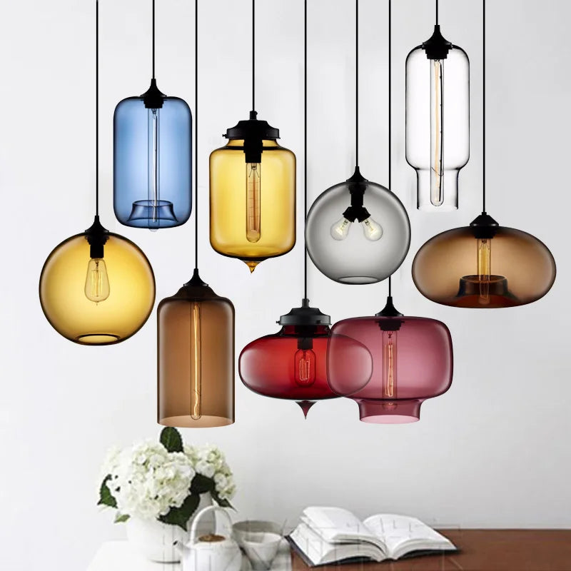 A collection of colorful translucent glass modern pendant lights with exposed bulbs and black metal fixtures for decor