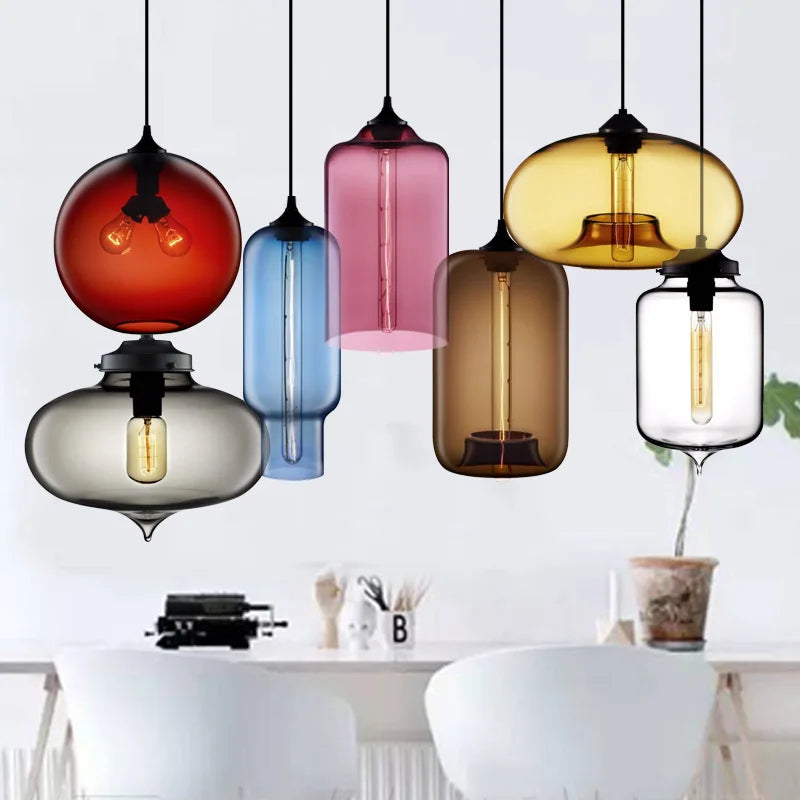 A collection of multicolored glass modern pendant lights with exposed filament bulbs hanging on black cords