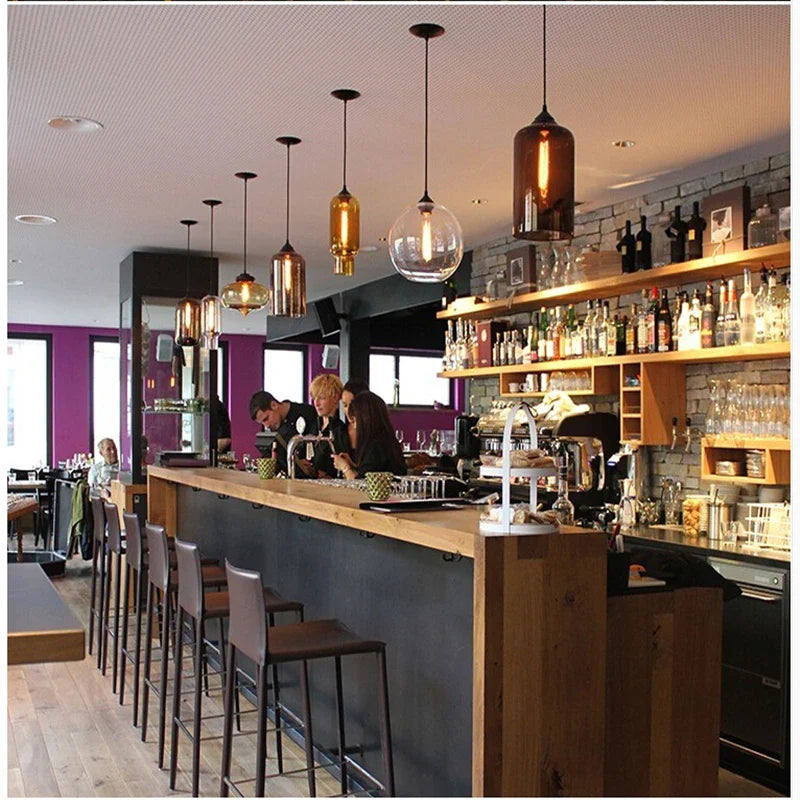 Warm amber and clear glass modern pendant lights hang above the bar for vintage loft and dining room decor