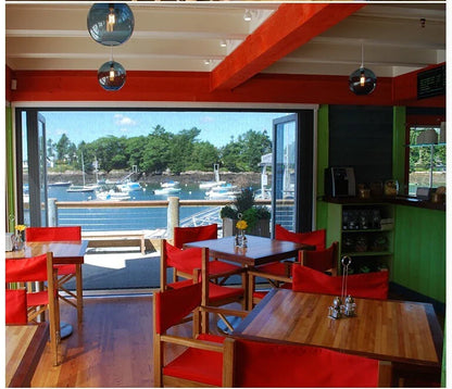 Red upholstered chairs with wooden frames complement modern pendant lights featuring multicolored glass for dining rooms