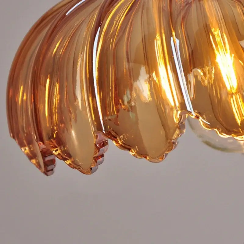 Amber-colored hand-blown glass led pendant lamp with scalloped petal design and brass cable for dining room lighting