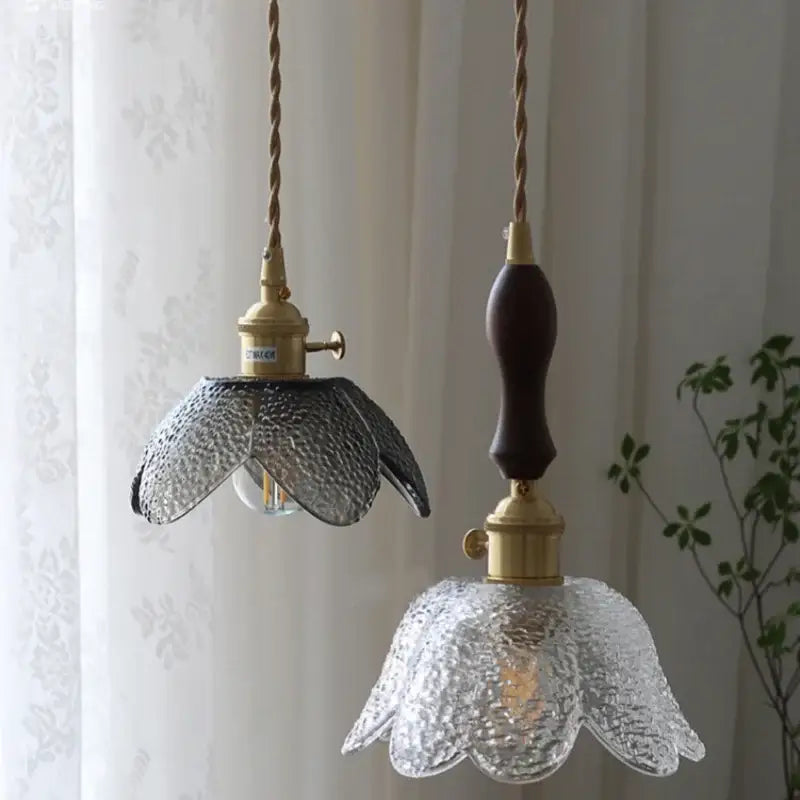 Two pendant lamps with textured clear glass LED flower shades and brass hardware, suspended by twisted rope cords